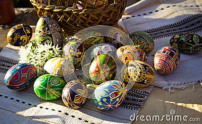 Colorful Easter eggs beside a basket on embroidered napkin Stock Photo